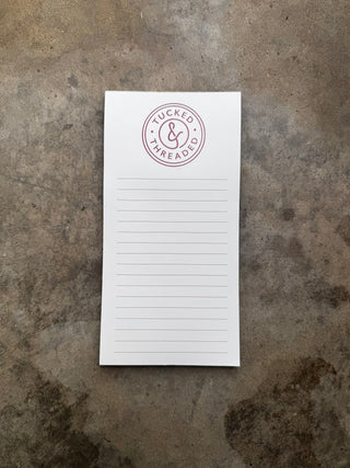 notepad with lines and Tucked & Threaded logo in mauve at the top