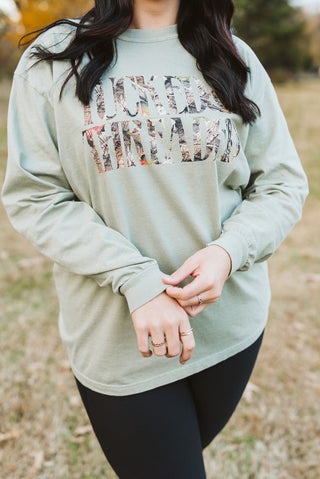 female model wearing a graphic tee that reads "tucked & threaded" in a camoflauge print