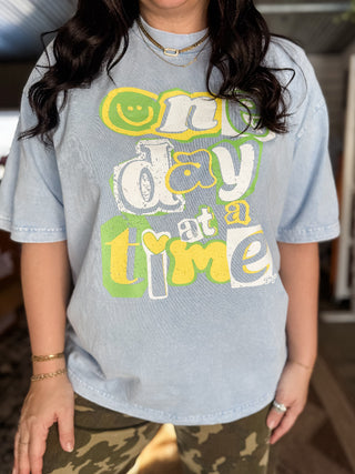 Person wearing a light blue t-shirt with colorful text design.