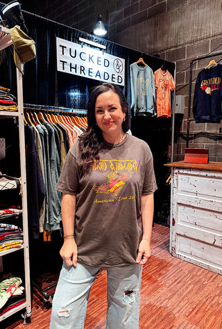 Woman wearing a t-shirt in a clothing store with 'Tucked & Threaded' branding.
