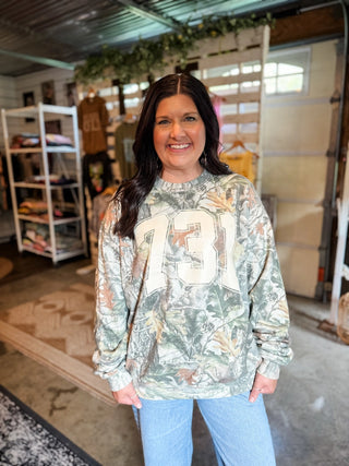 female model in she-shed of tucked & threaded in greenfield, tn wearing a 731 area code camo sweatshirt