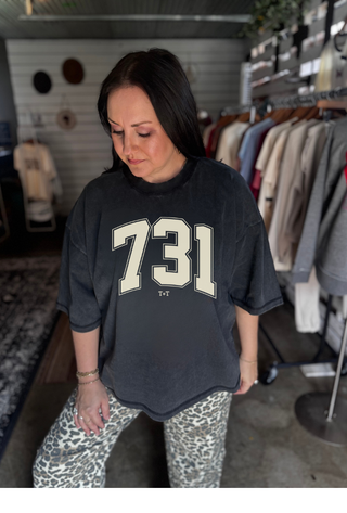 Woman wearing a black oversized t-shirt with '731' printed on it in a clothing store.