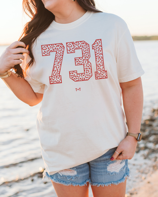 Person wearing a white t-shirt with red numbers '731' at the beach