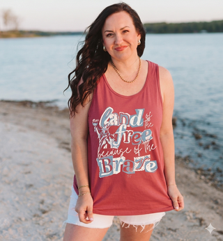 Woman wearing a tank top with text on it, standing on a beach.