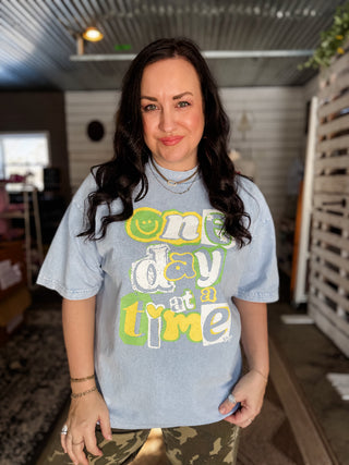 Woman wearing a light blue t-shirt with colorful text in an indoor setting