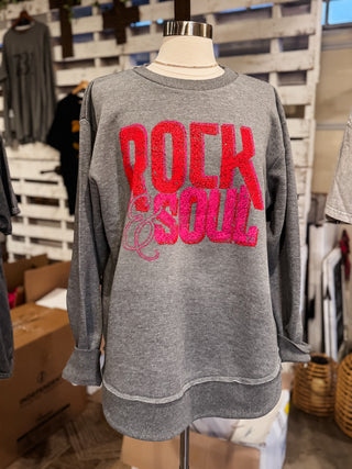 Gray sweatshirt with red and pink 'Rock & Soul' text on a mannequin in a store setting.