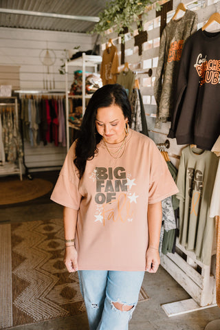 big fan of fall over sized graphic tee in a nude color  worn by a female model that reads "big fan of fall" paired with blue jeans in a she-shed