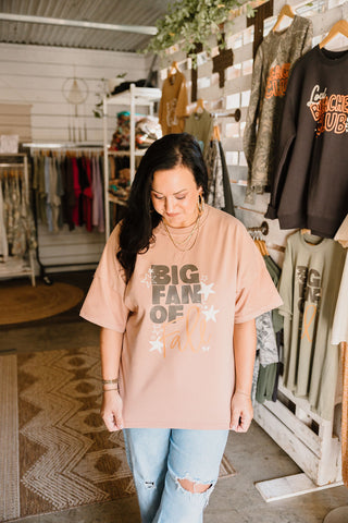 big fan of fall over sized graphic tee in a nude color  worn by a female model that reads "big fan of fall" paired with blue jeans in a she-shed