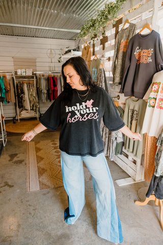 graphic boxy tee being featured with a design that reads "hold your horses" worn with blue jeans by female model