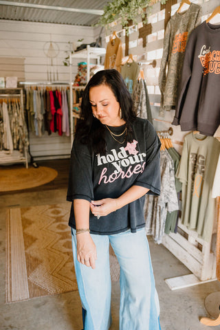 female model in she-shed modeling a boxy faded black graphic tee with blue jeans