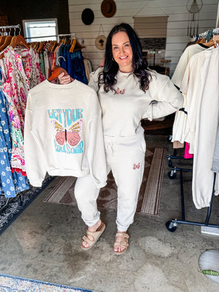 Woman holding a sweatshirt with text and graphics in a clothing store.