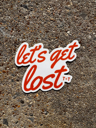 Sticker with 'let's get lost' text on a textured surface