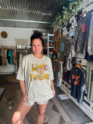 female model in a she-shed wearing work out shorts with a graphic tee in a solid leopard natural color with a graphic design printed on the front in plum, gold, coral, and green inks that reads "live on purpose"