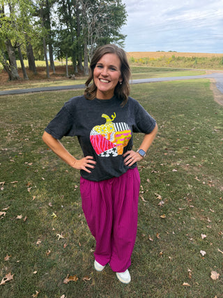 female model outside in grass with pink pants and black vintage patchy pumpkin design