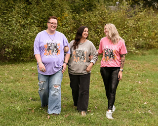 3 female models in a field with graphic tee and sweatshirt on that reads "queens of halloween"
