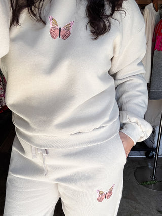 Person wearing a white tracksuit with pink butterfly designs.