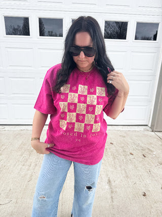 Woman wearing a pink graphic t-shirt and sunglasses in front of a white garage door.