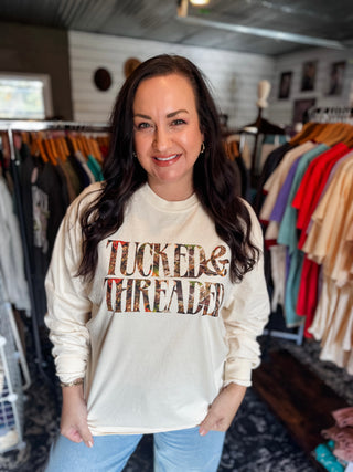 Woman wearing a 'Tucked & Threaded' sweatshirt in a clothing store.