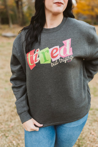 Person wearing a dark gray sweatshirt with colorful text in an outdoor setting