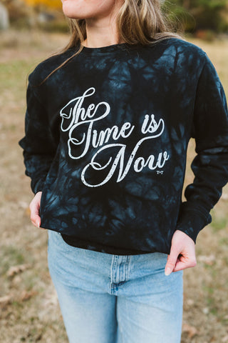 model in ladies graphic tie-dye black sweatshirt with design in white ink that reads "the time is now"