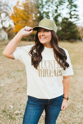 female brunette model modeling an ivory oversized midweight american apparel cotton tee. the graphic print reads "tucked & threaded" in a khaki ink.