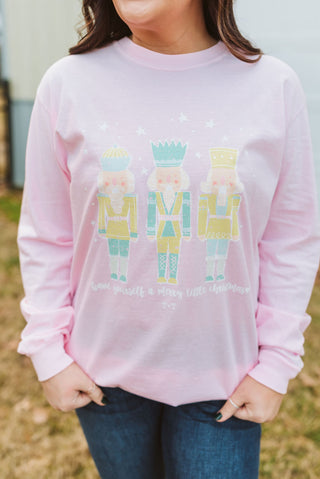 Person wearing a pink long-sleeve shirt with colorful graphic design outdoors.