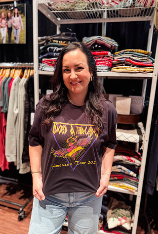 young lady wearing a black tee with a screen print design reading "tucked and threaeded" american tour 2026 on the front of the tee